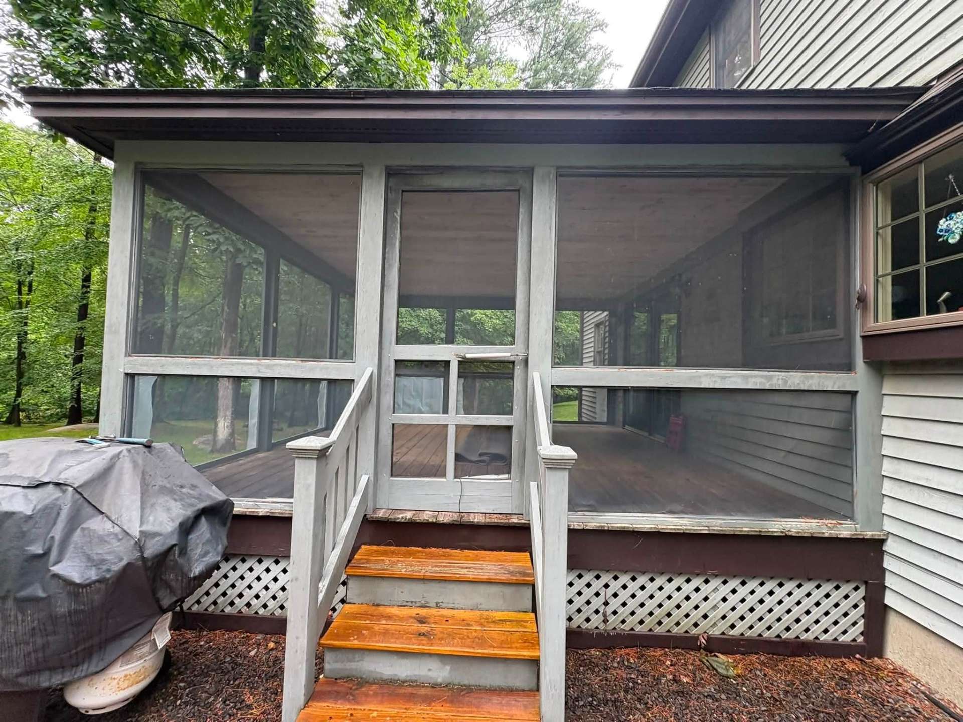 Before: weathered screened-in porch with gray wood framing and an old screen door in Atkinson, NH